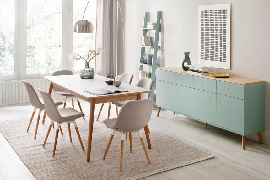 A Scandi sideboard in soft pastel green stands out in this dining space. Image by designbotschaft GmbH.